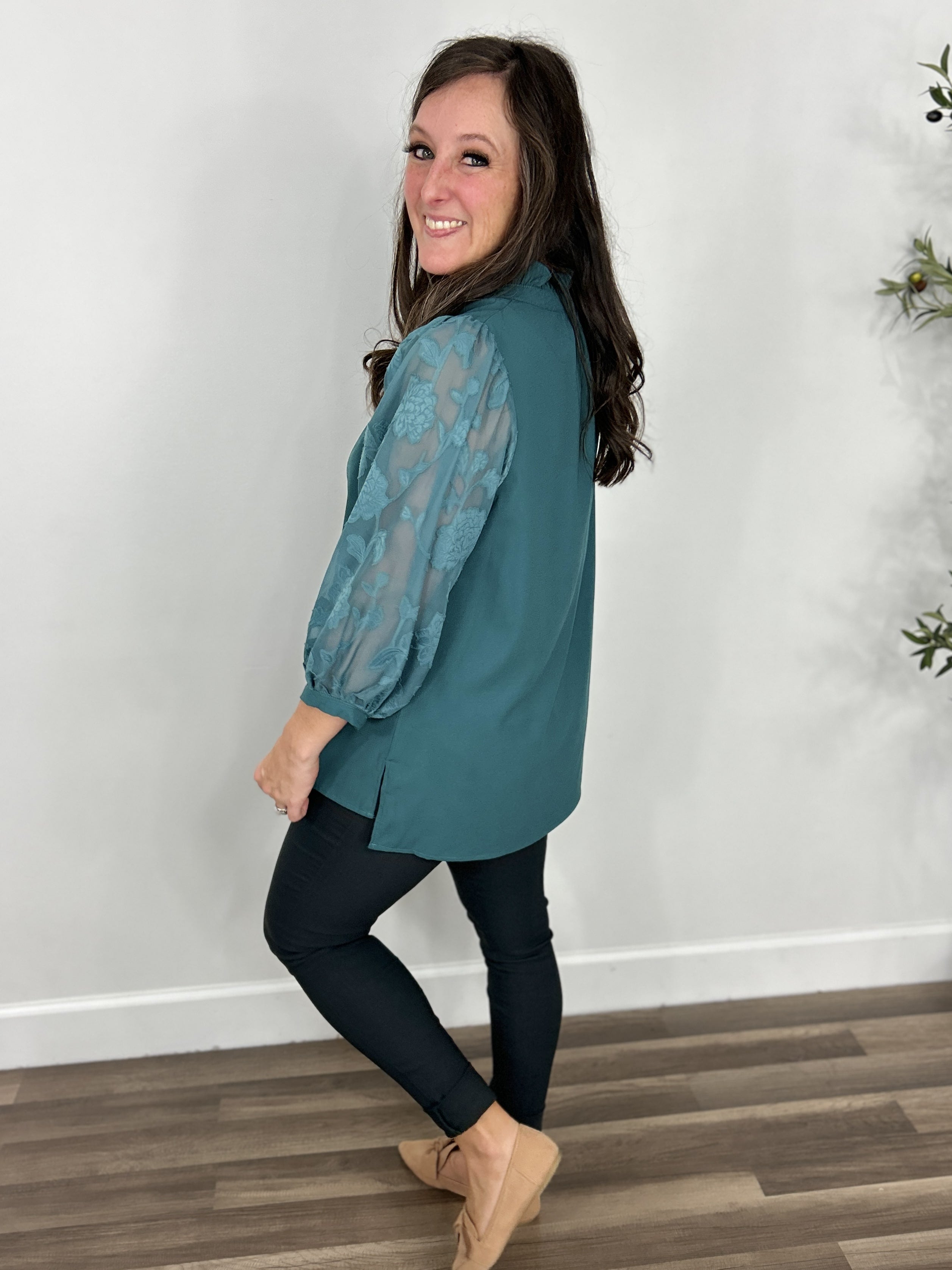 Teal women's three quarter sleeve top side view paired with skinny pants and flat shoes.