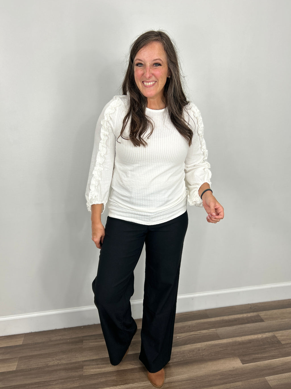 Adley frilled long sleeve ivory top paired with black straight leg denim and brown boots