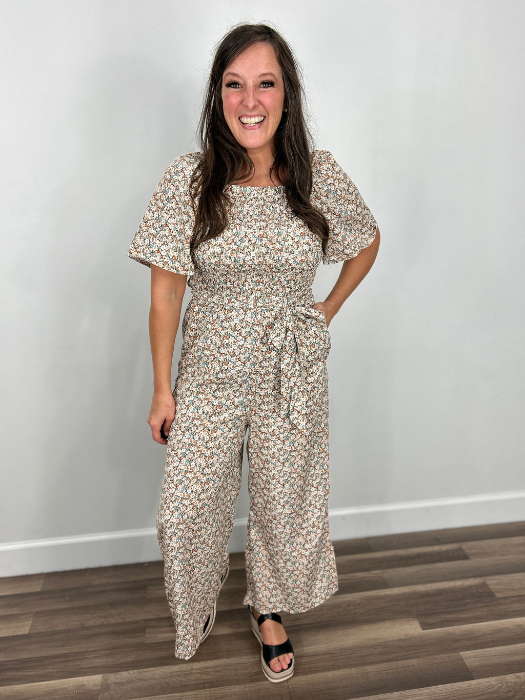 Women's Adriann floral short sleeve jumpsuit paired with black wedge sandals.