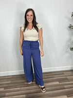 Load image into Gallery viewer, Outfit styled with the banks striped butterfly cap sleeve in ivory and brown paired with blue linen wide leg pants and black wedge sandals.
