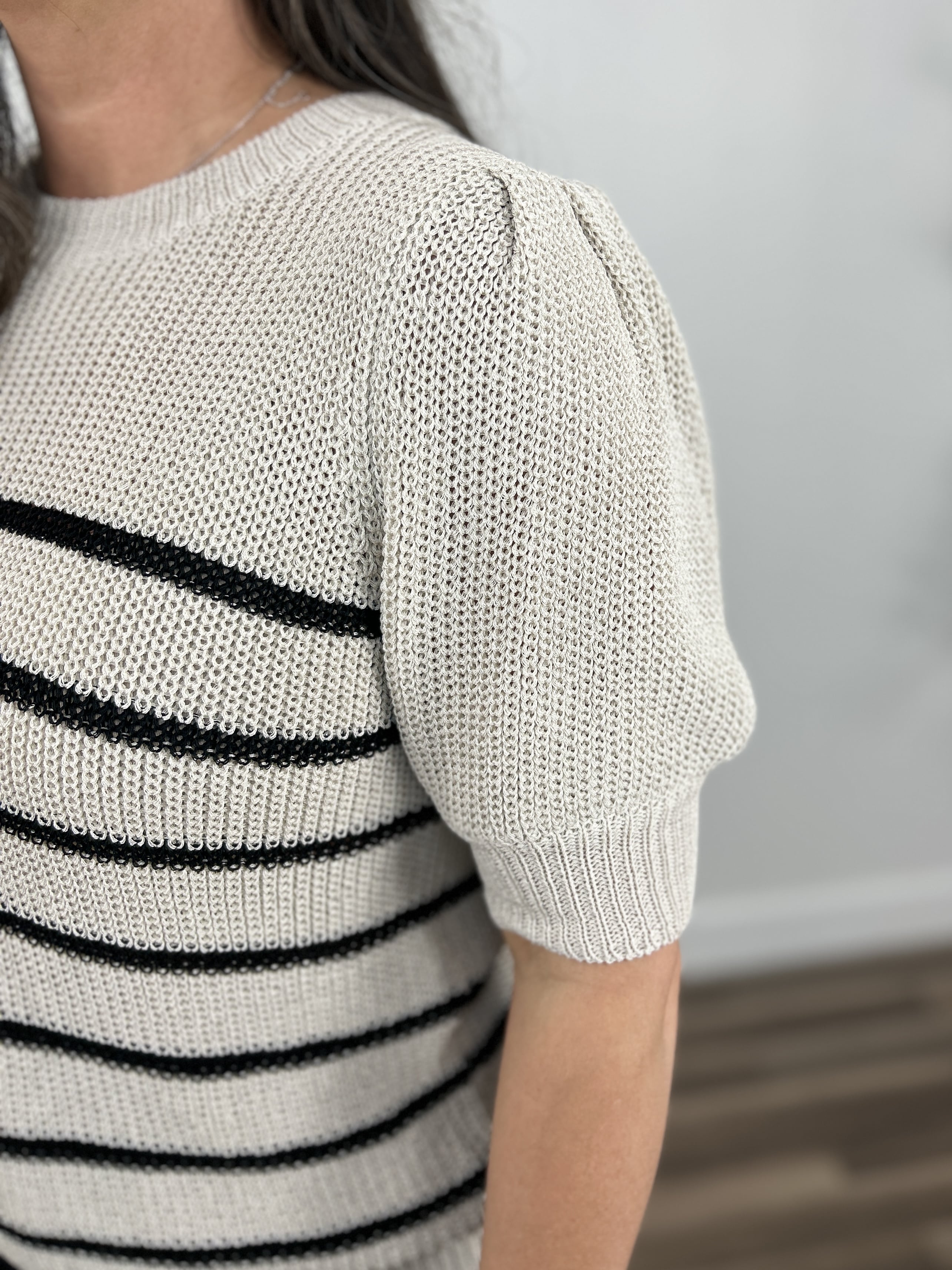 Upclose detailing of the puff short sleeve on the taupe and black striped knit sweater top.