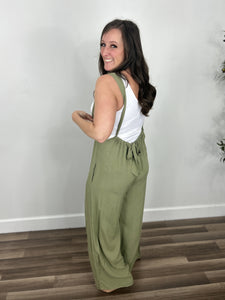 Women's green jumpsuit back view of bow tie detailing.