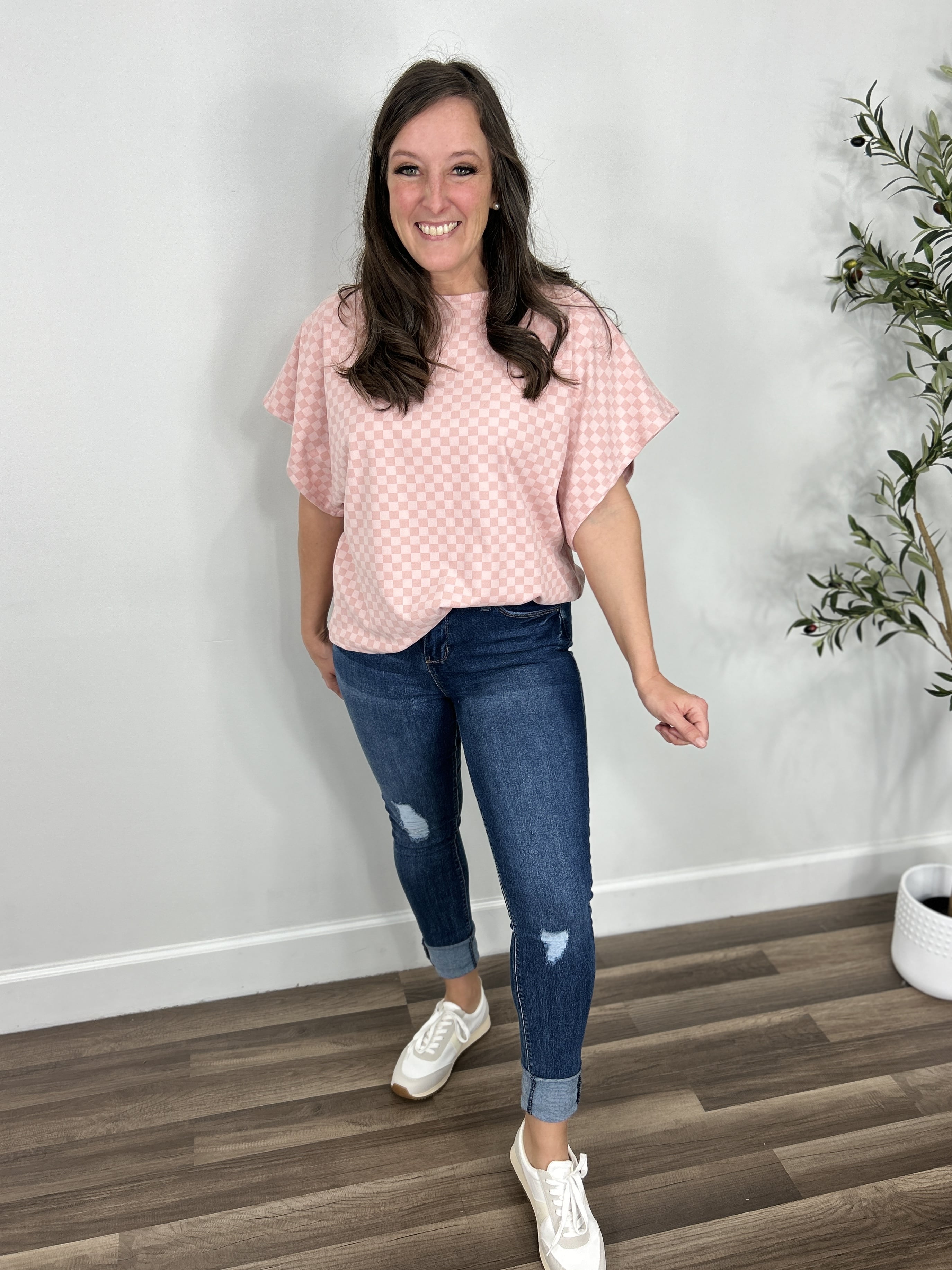 Two tone pink checker women's top paired with blue jeans and sneakers.
