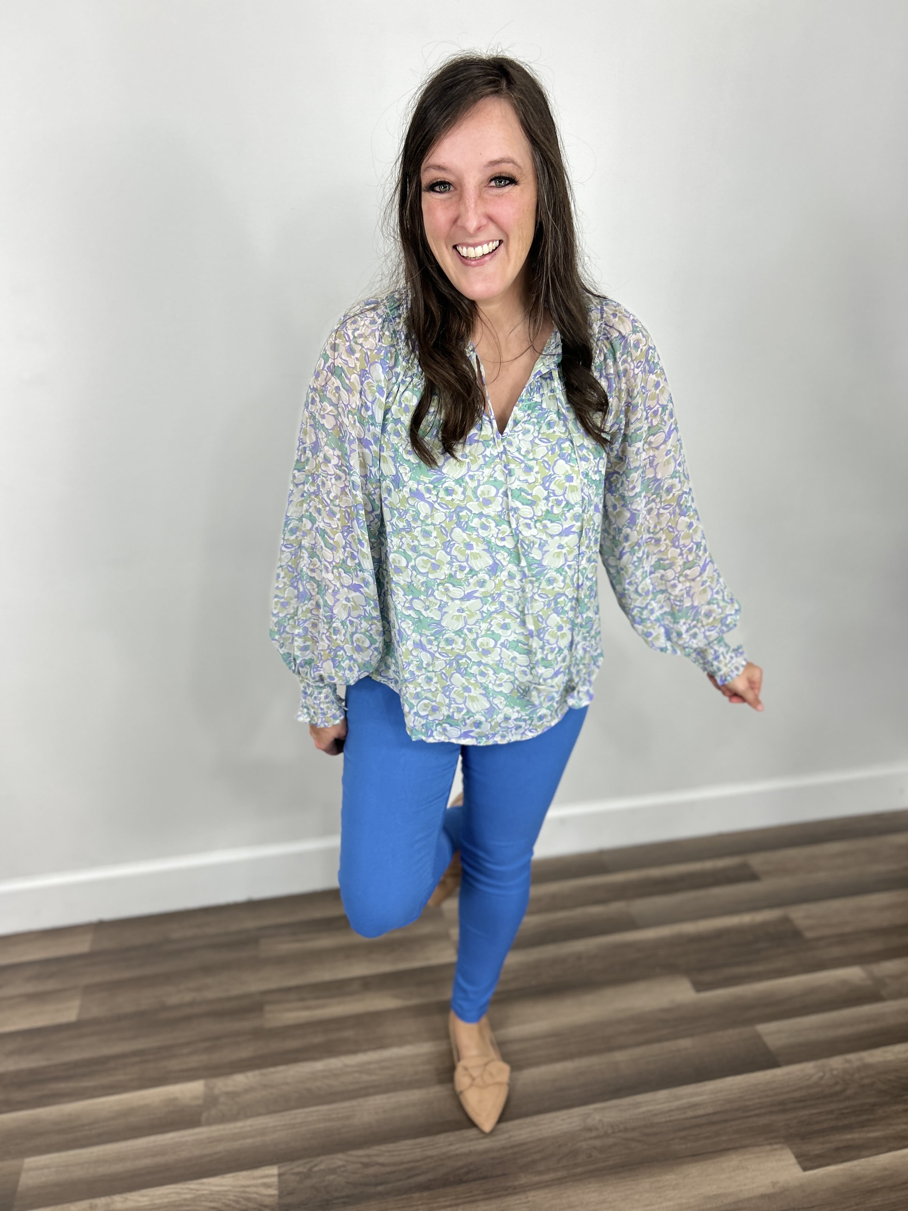 Women's floral print long sleeve top paired with blue stretchy skinny jeans.
