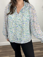 Load image into Gallery viewer, Women&#39;s floral print top upclose view of smocked neckline and decorative neck tassels.
