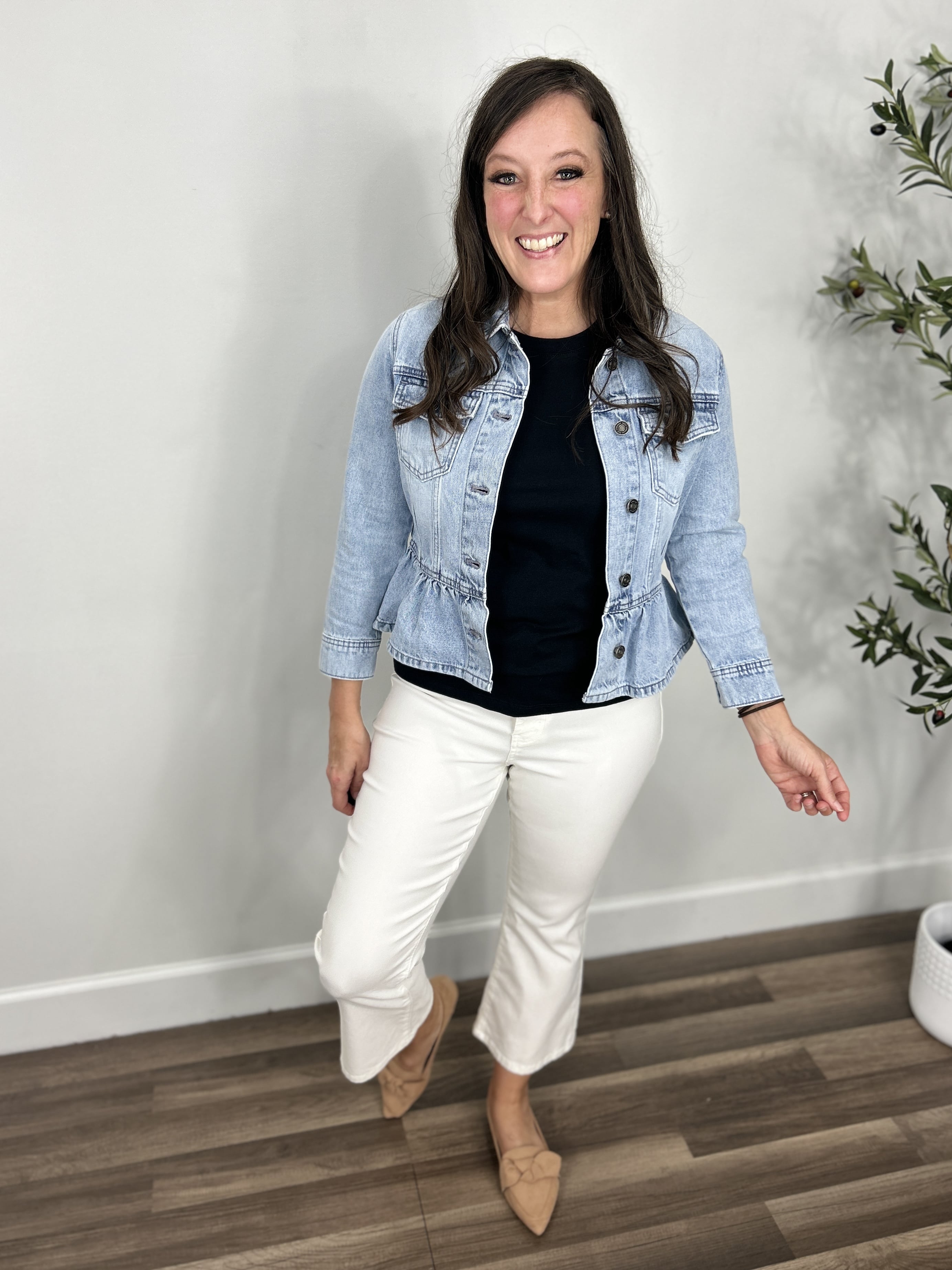 Outfit styled with the Emma Peplum Lightwash Denim jacket. Layered with a black tee shirt and paired with white crop flare pants.