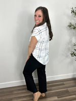 Load image into Gallery viewer, Back view of the blue and white Franklin plaid button down top paired with black denim and camel flat shoes.
