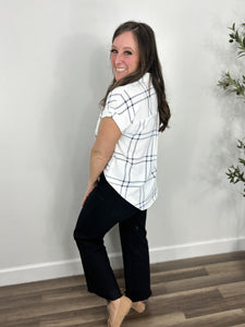 Back view of the blue and white Franklin plaid button down top paired with black denim and camel flat shoes.