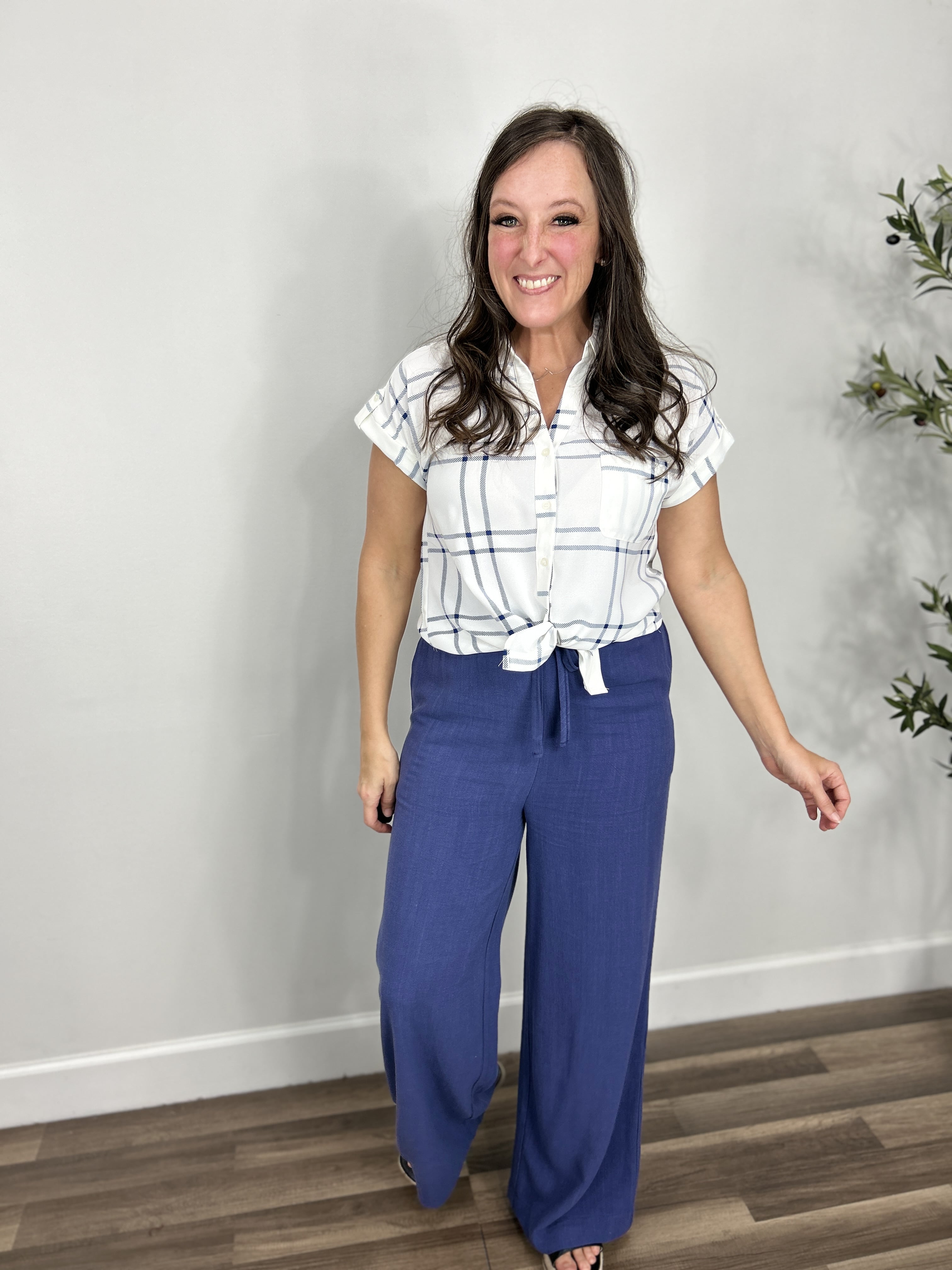 Women's Franklin Plaid Button Down Top with short sleeves and fold over collar tied in a front knot paired with blue wide leg pants.