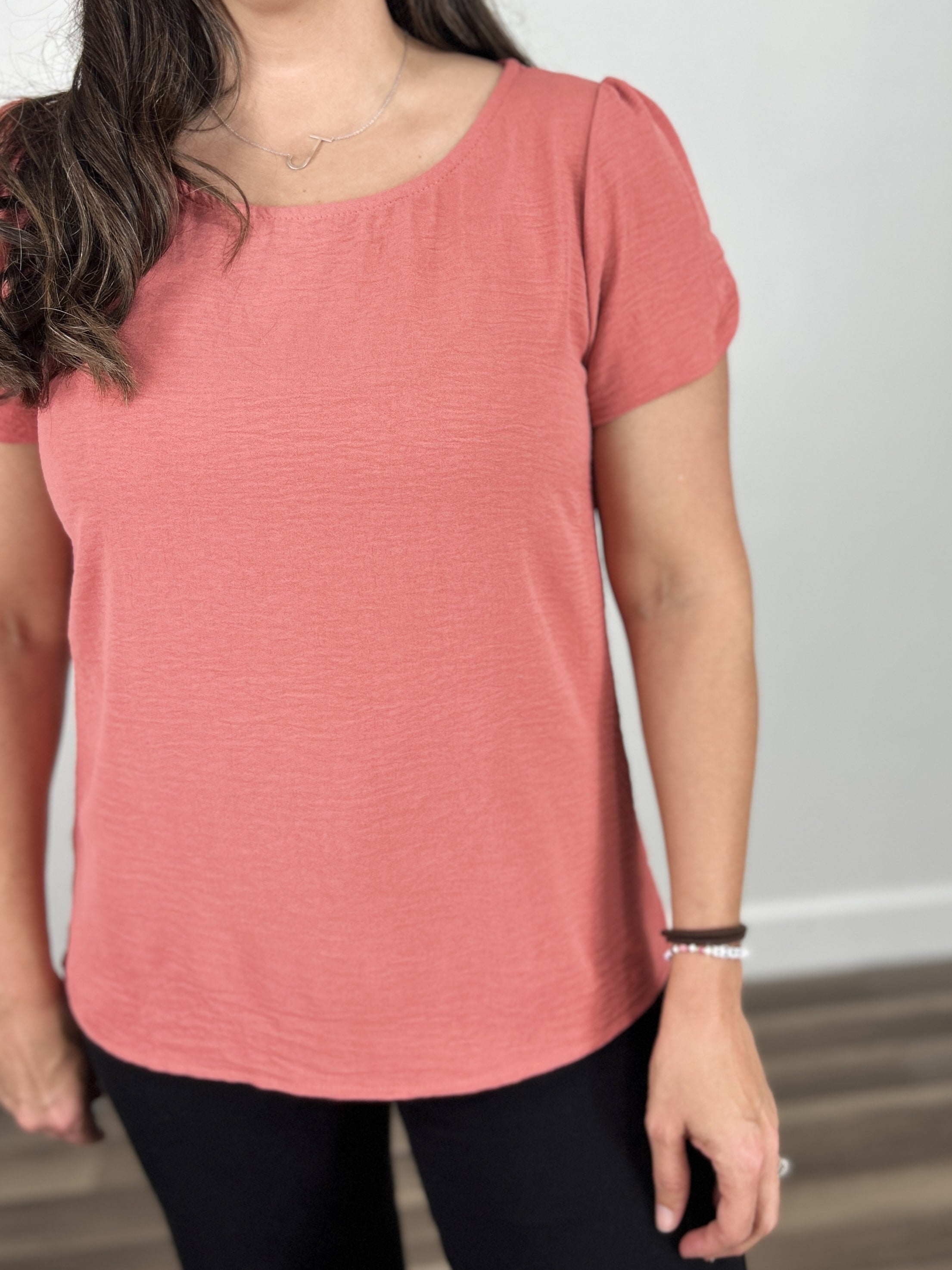 Upclose view of the Ginger round neck short sleeve top coral color and wavy texture material.