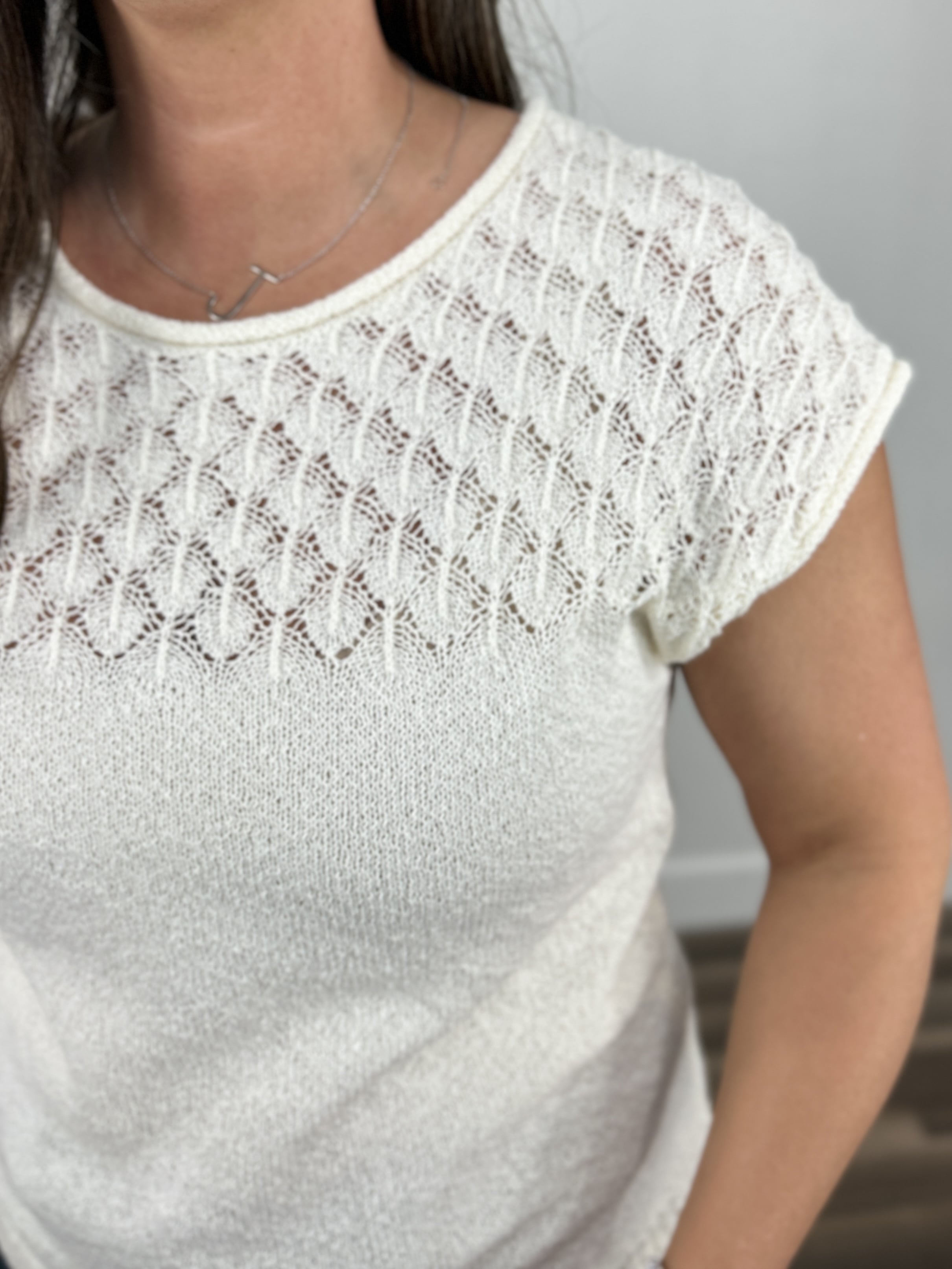 Detailed view of the off white gracelynn cap sleeve sweater top showing off the eyelet yoke.