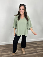 Load image into Gallery viewer, Haven Bubble Sleeve V Neck Top paired with black wide leg denim and taupe sandals.
