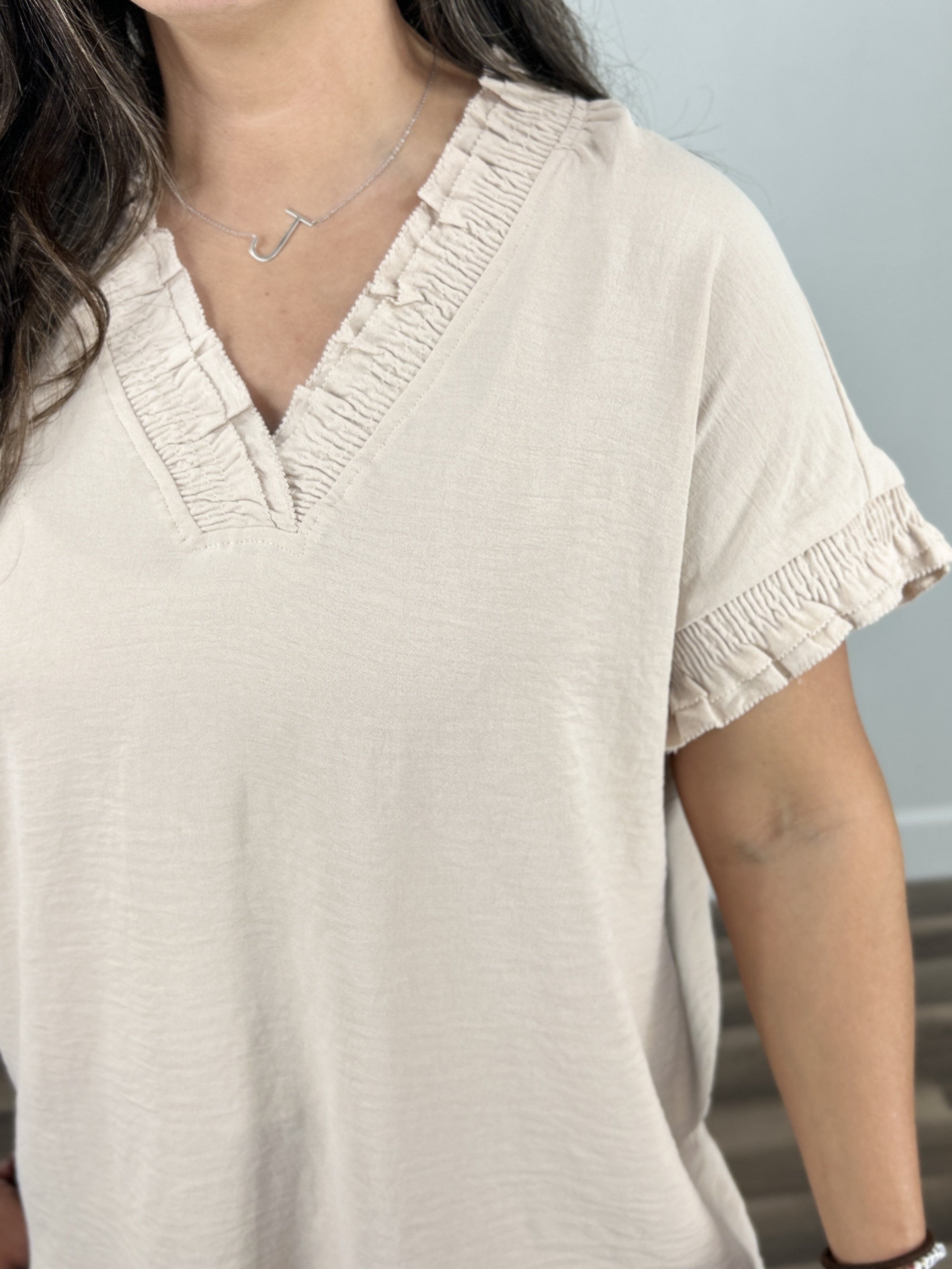 Detailed view of the Kara Cap sleeve v neck top showing the ruching around neck and sleeves as well as the small ruffle on neck and sleeves. 