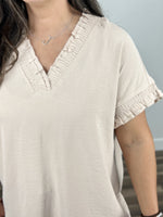Load image into Gallery viewer, Detailed view of the Kara Cap sleeve v neck top showing the ruching around neck and sleeves as well as the small ruffle on neck and sleeves. 
