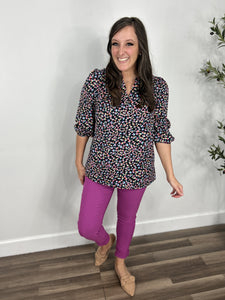 Outfit styled- women's mixed bright color leopard print top with three quarter sleeve and v neckline paired with pink color skinny jeans and flat shoes.