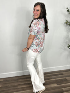 Back and side view of the Kenzie floral puff short sleeve top paired with white flare pants and black wedge sandals. 