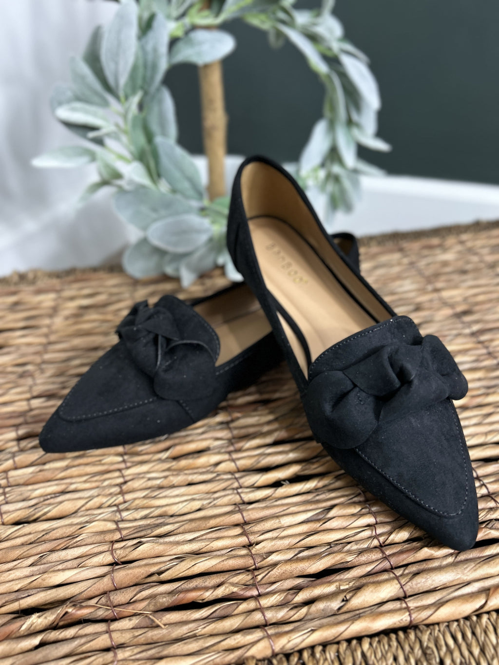 Women's black slip on flats with pointed toe and decorative bow tie on top.