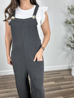 Load image into Gallery viewer, Upclose view of the charcoal ribbed texture of the Kobe Jumpsuit with front pockets and tortoise button claps on chest. 
