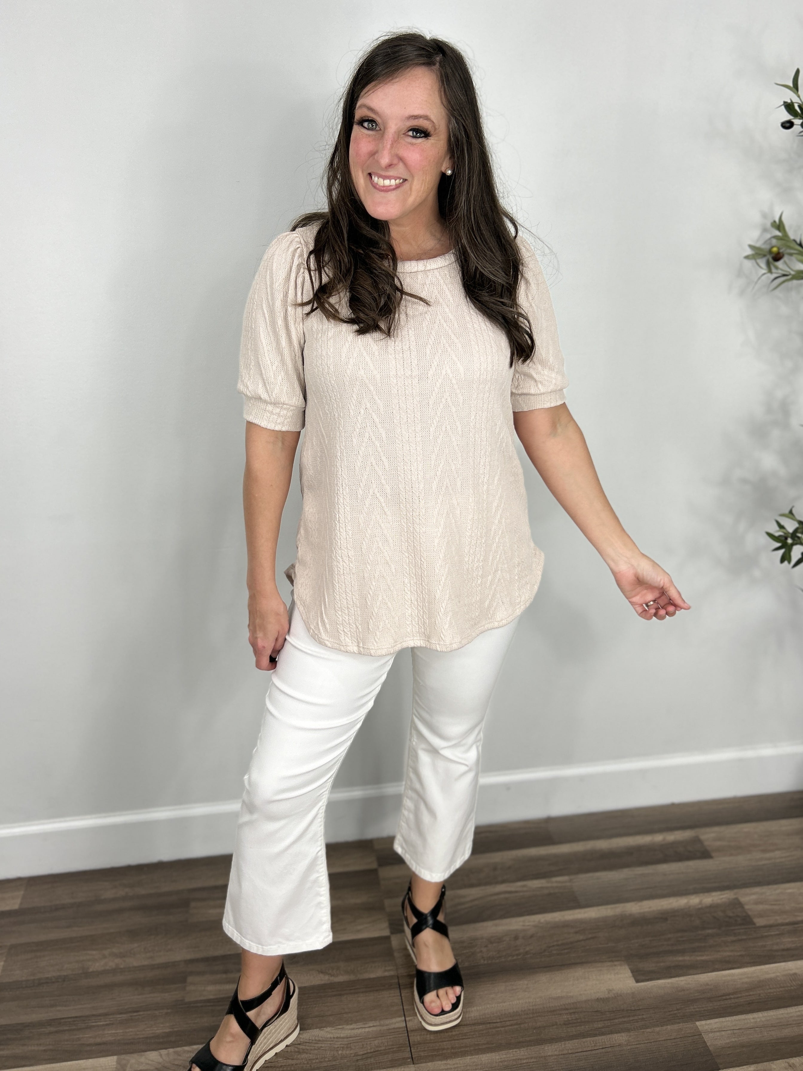 Women's oatmeal color short sleeve cable knit top paired with white crop flare pants and black wedge shoes.