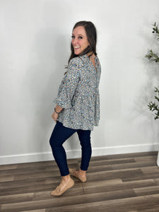 Side and back view of the Malloy floral babydoll v neck top showing the 3/4 sleeves. Paired with navy skinny jeans and flat camel color flats.
