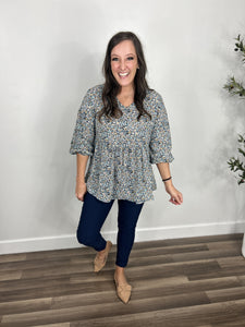 Women's mallory blue floral babydoll v neck top with three quarter sleeves paired with navy blue skinny jeans and paired with flat camel color shoes.