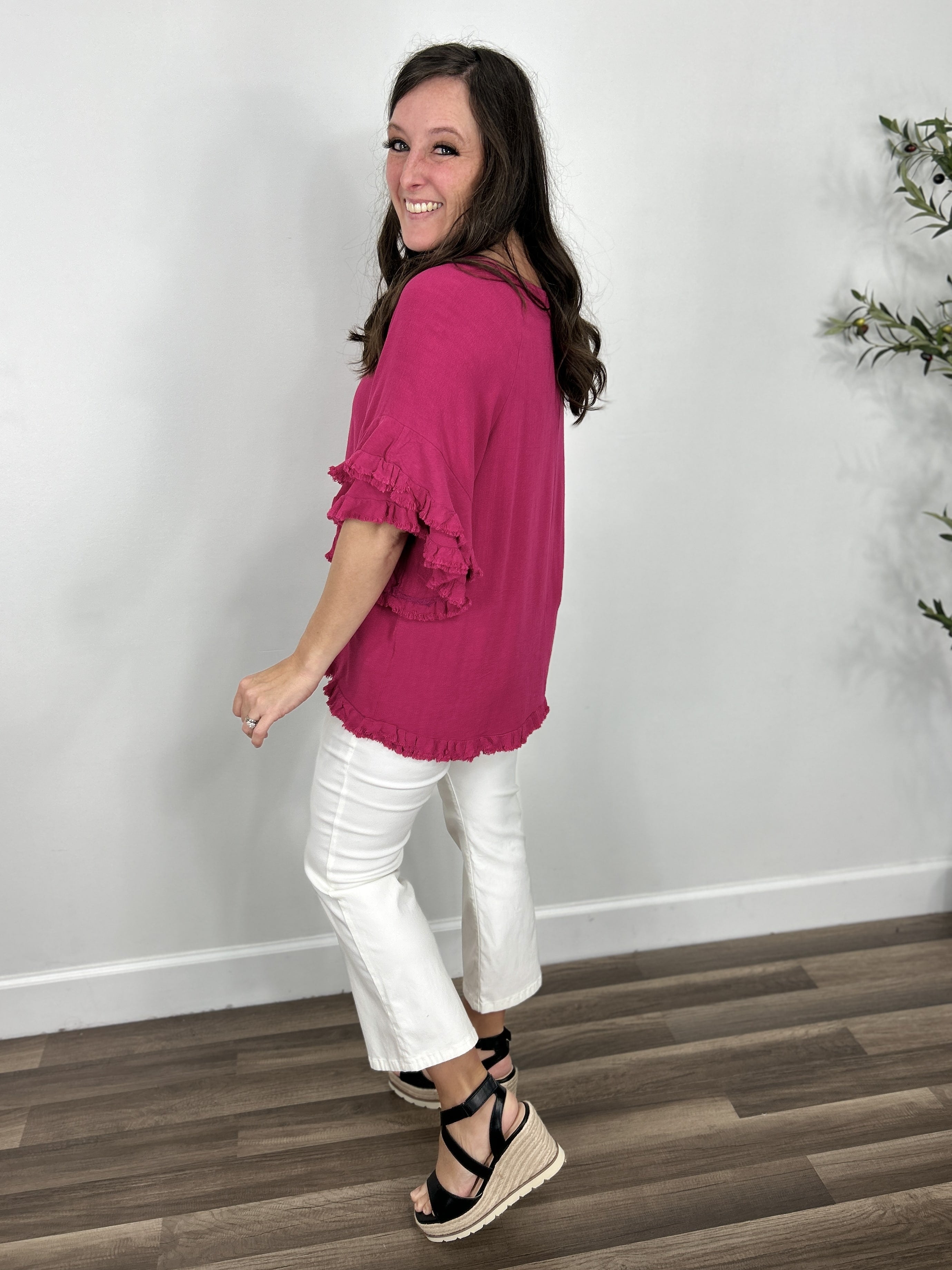 Side and back view of the Meredith linen ruffle sleeve top in hot pink with white crop flare pants and black sandals.