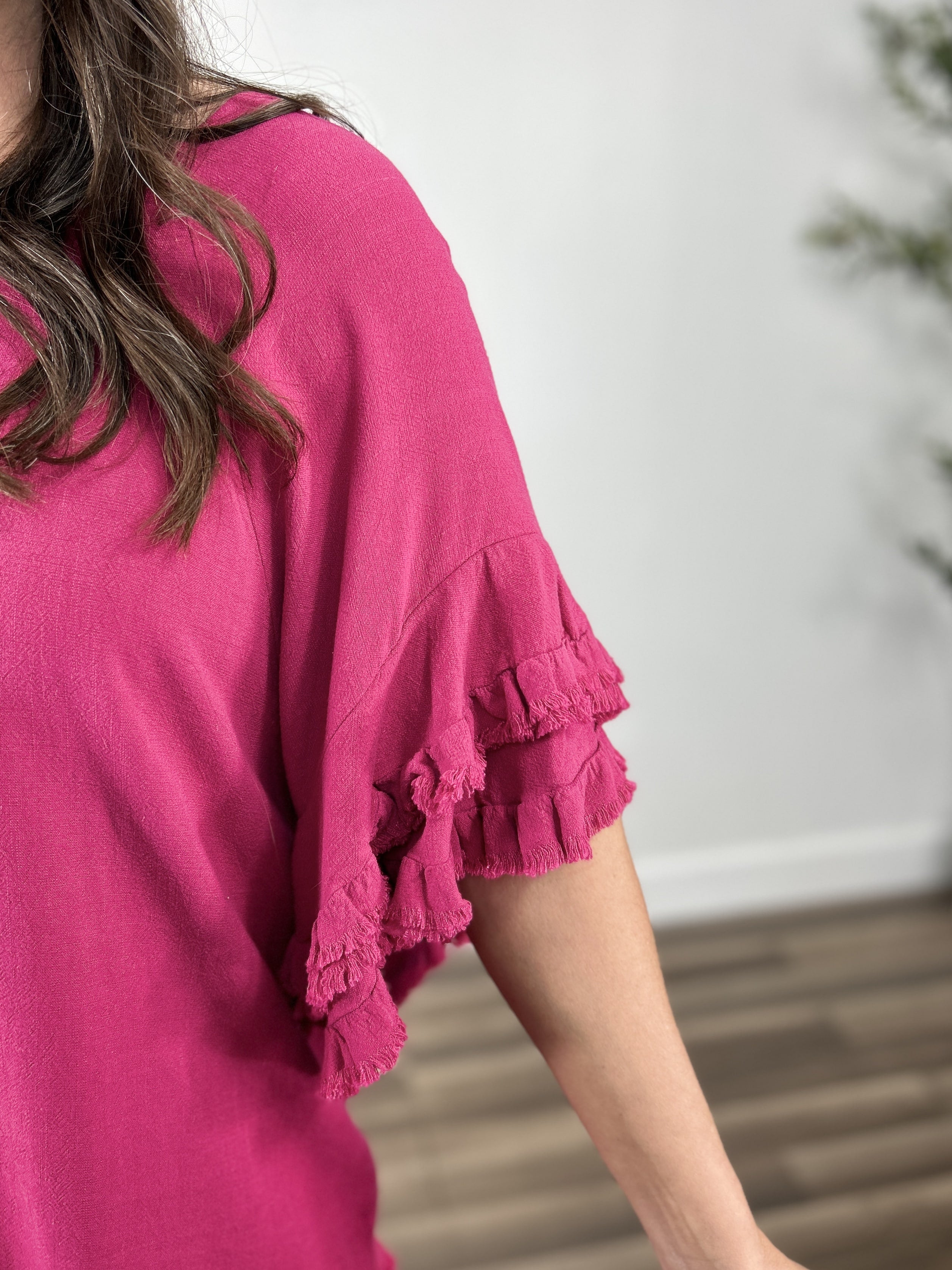 Upclose view of the women's fuchsia color ruffle sleeve top. Showing the double tier ruffle with frayed hem detailing.