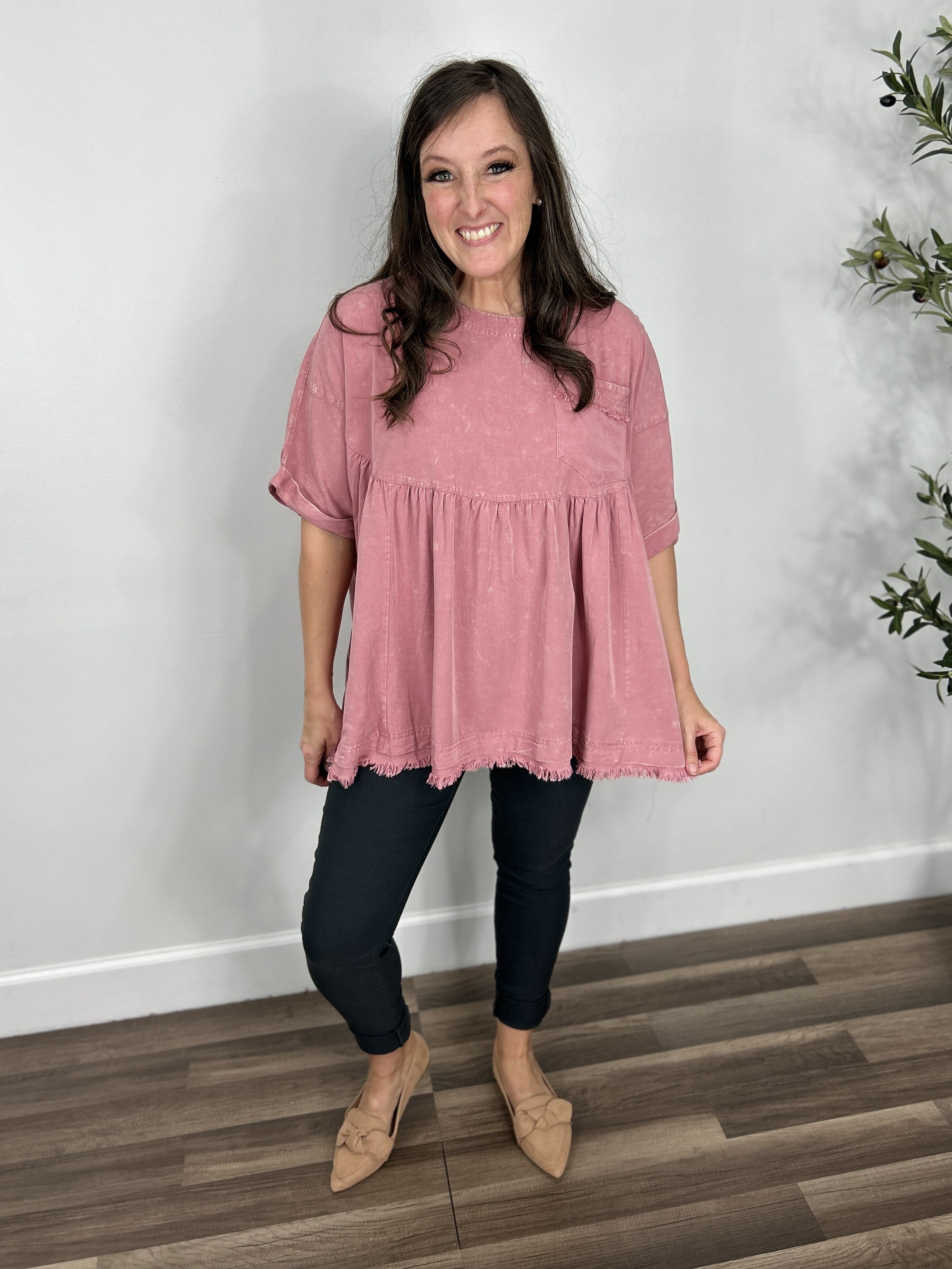 Women's mineral wash pink short sleeve oversized babydoll top paired with charcoal skinny jeans and paired with camel color flat shoes.