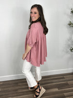 Load image into Gallery viewer, Side view of the women&#39;s mineral wash pink oversized babydoll top showing the slight hi low hem and rolled sleeve cuff.
