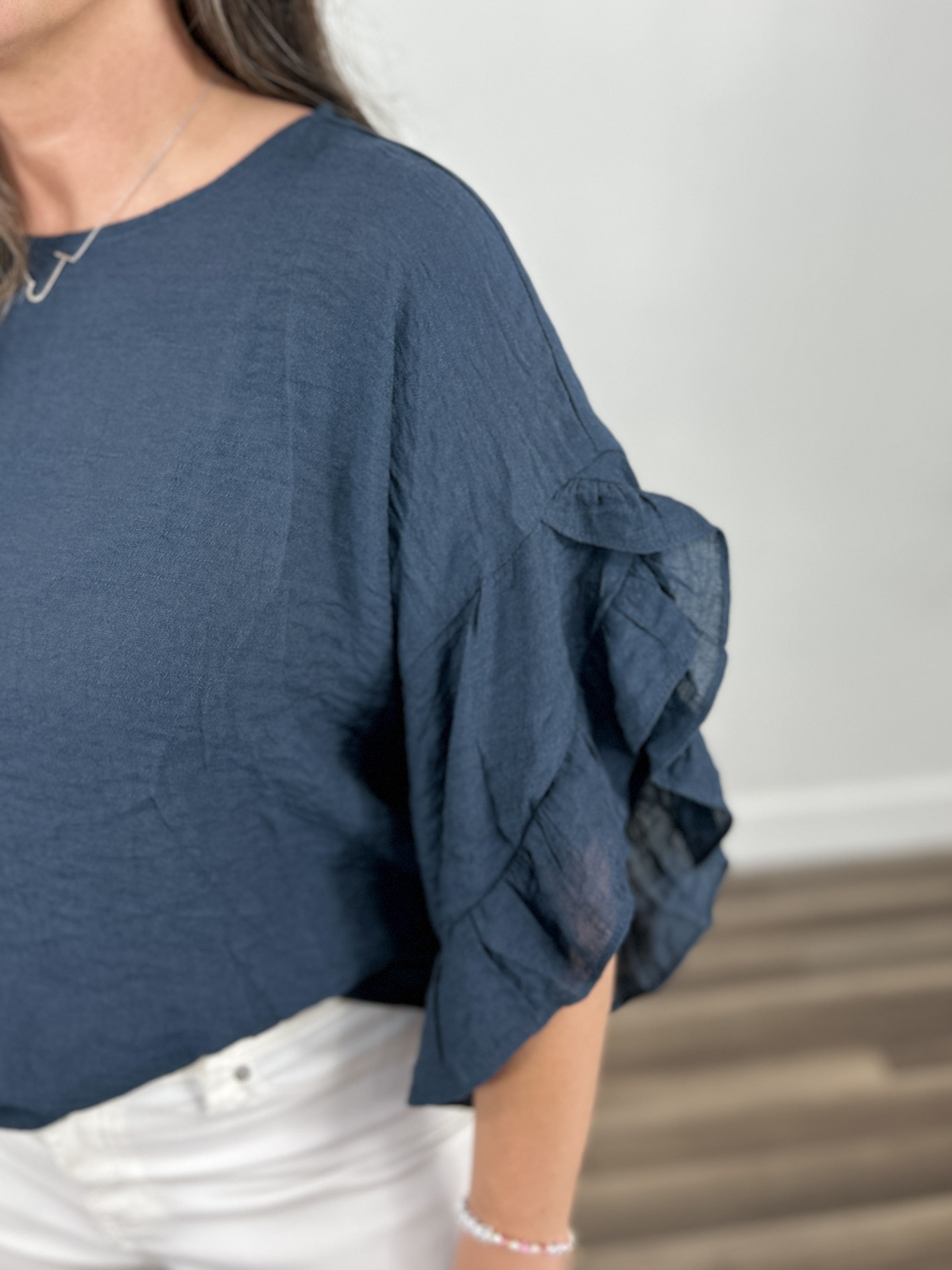 Detailed view of the three quarter sleeve ruffle detail on the women's Rigsby Top.