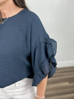 Load image into Gallery viewer, Detailed view of the three quarter sleeve ruffle detail on the women&#39;s Rigsby Top.
