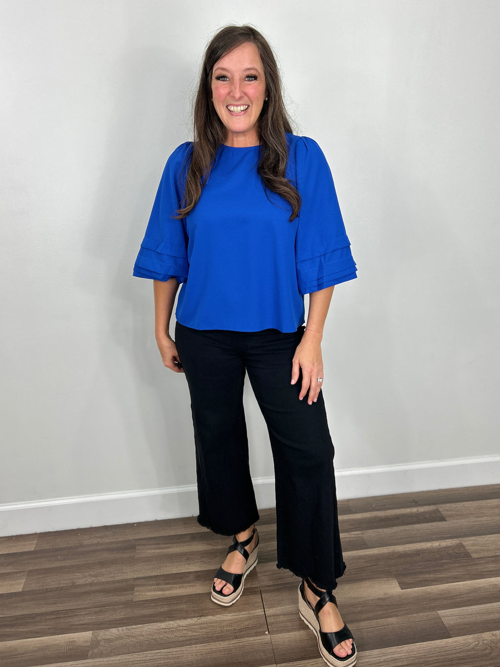 Women's Sapphire three quarter sleeve back tie top in royal blue paired with black denim crop pants and black wedge sandals.