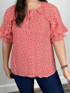 Upclose view of the Scarlett floral short sleeve top with white flowers on a red background.