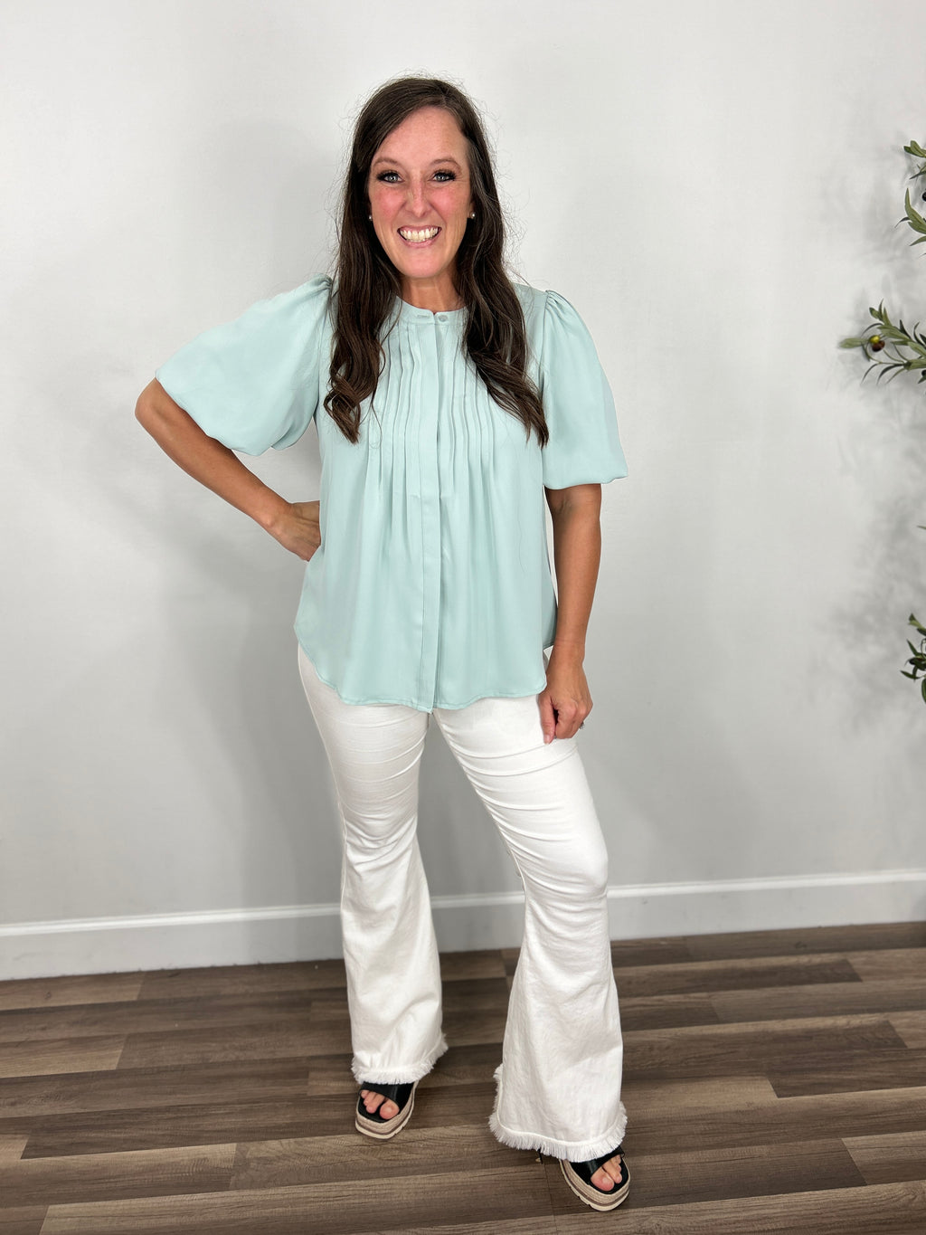 Women's Sophie bubble sleeve button down top in dusty blue paired with white flare jeggings and black wedge sandals.
