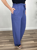 Load image into Gallery viewer, Side view of the Tate Linen Wide leg pant in blue with hand in pocket.

