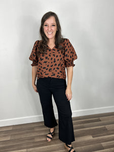 black and brown leopard print women's top front tucked into black wide leg denim pants and completed with black wedge sandals.