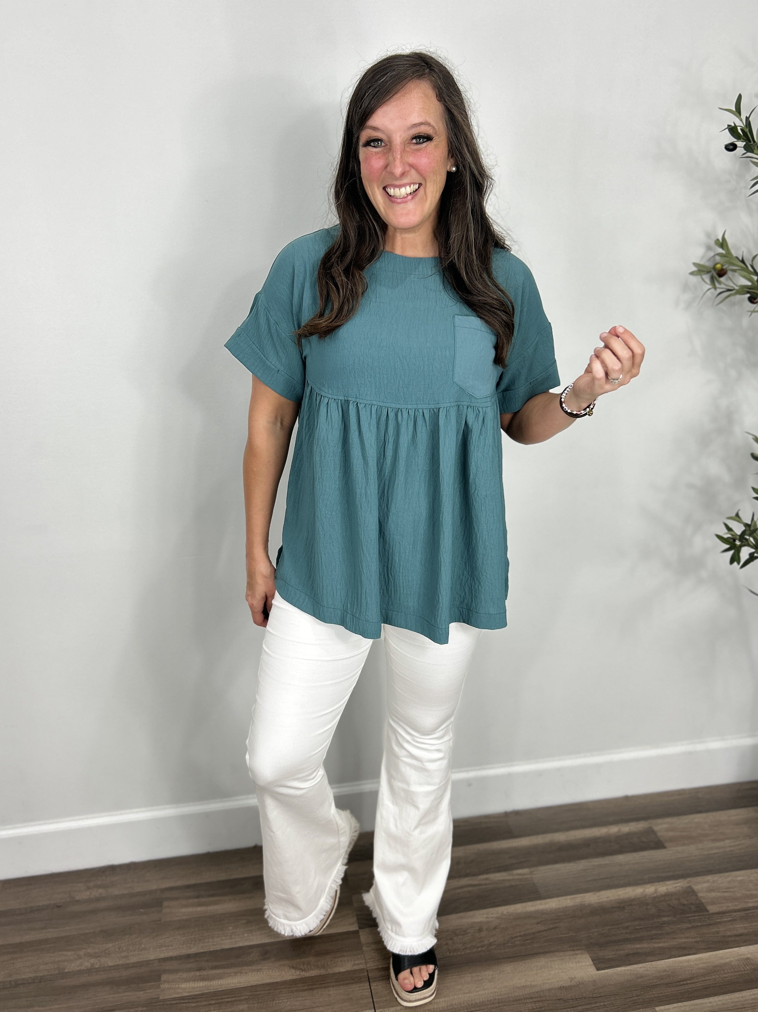 Women's Whitney short sleeve babydoll top in teal paired with the Olivia stretchy flare jeggings in white with black wedge sandals.